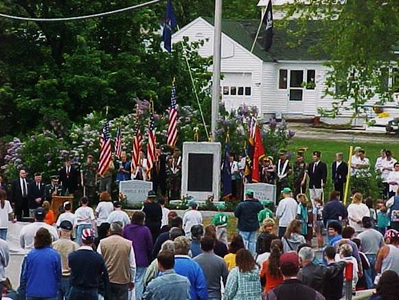 A group of people standing in front of a memorial
Description automatically generated